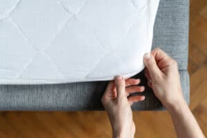 top view of hand putting on mattress topper on couch